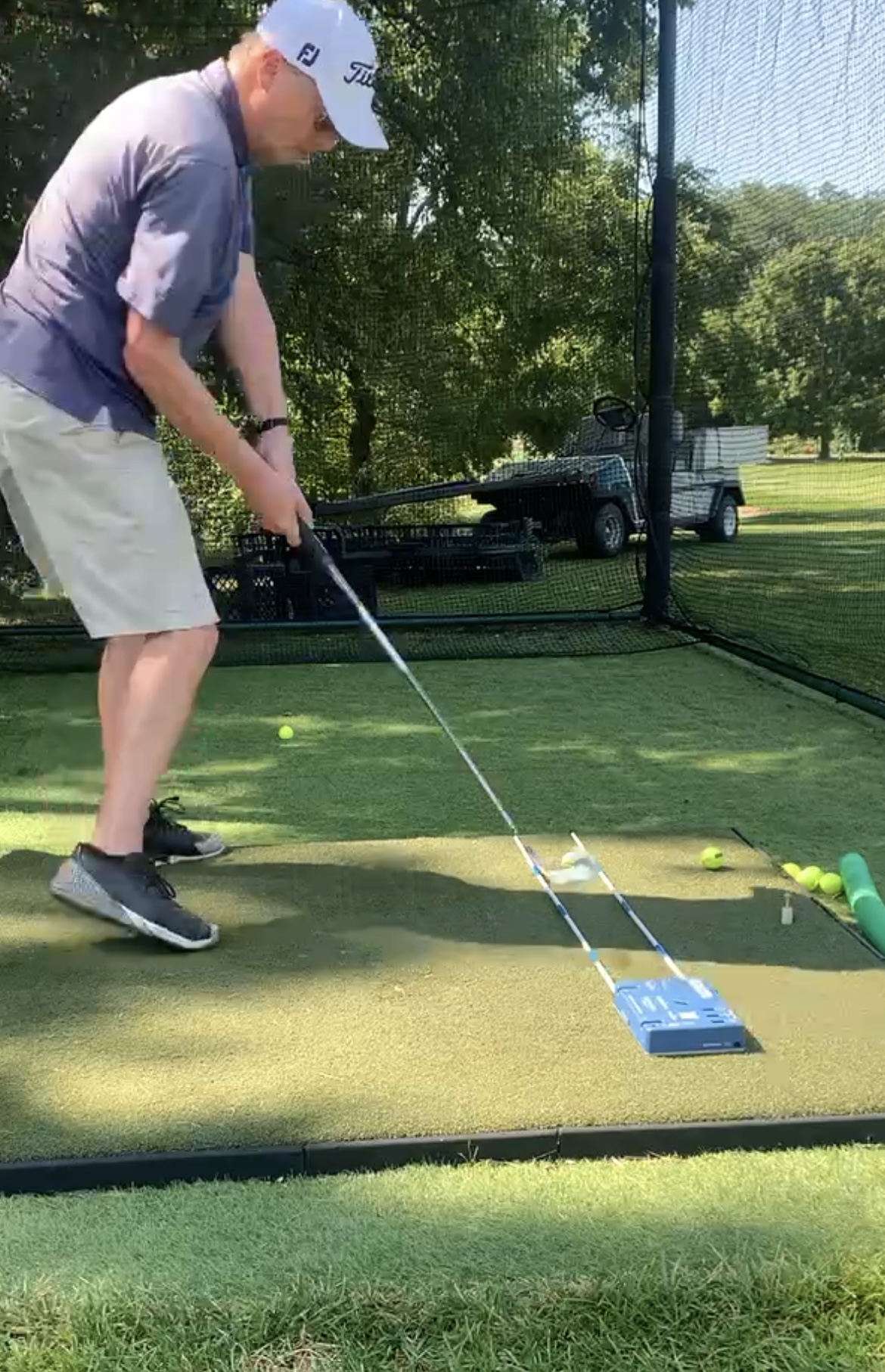 Golfer striking the ball between two alignment sticks that guide the club path